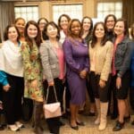 Group of women gathered indoors, smiling for a photo.