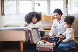 Mother and daughter packing a suitcase together in a bright room.