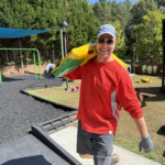 Man carrying bag at playground, smiling.