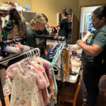 Volunteers organizing children’s clothes on racks.