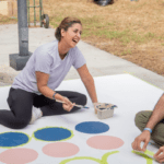 People painting circles, smiling and chatting outdoors.